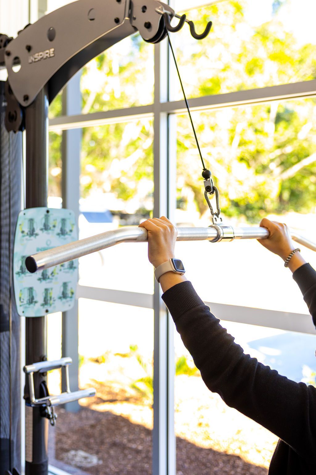 Person using a cable machine for seated lat pulldowns in a bright gym — Forerunner Physio In Taree, NSW
