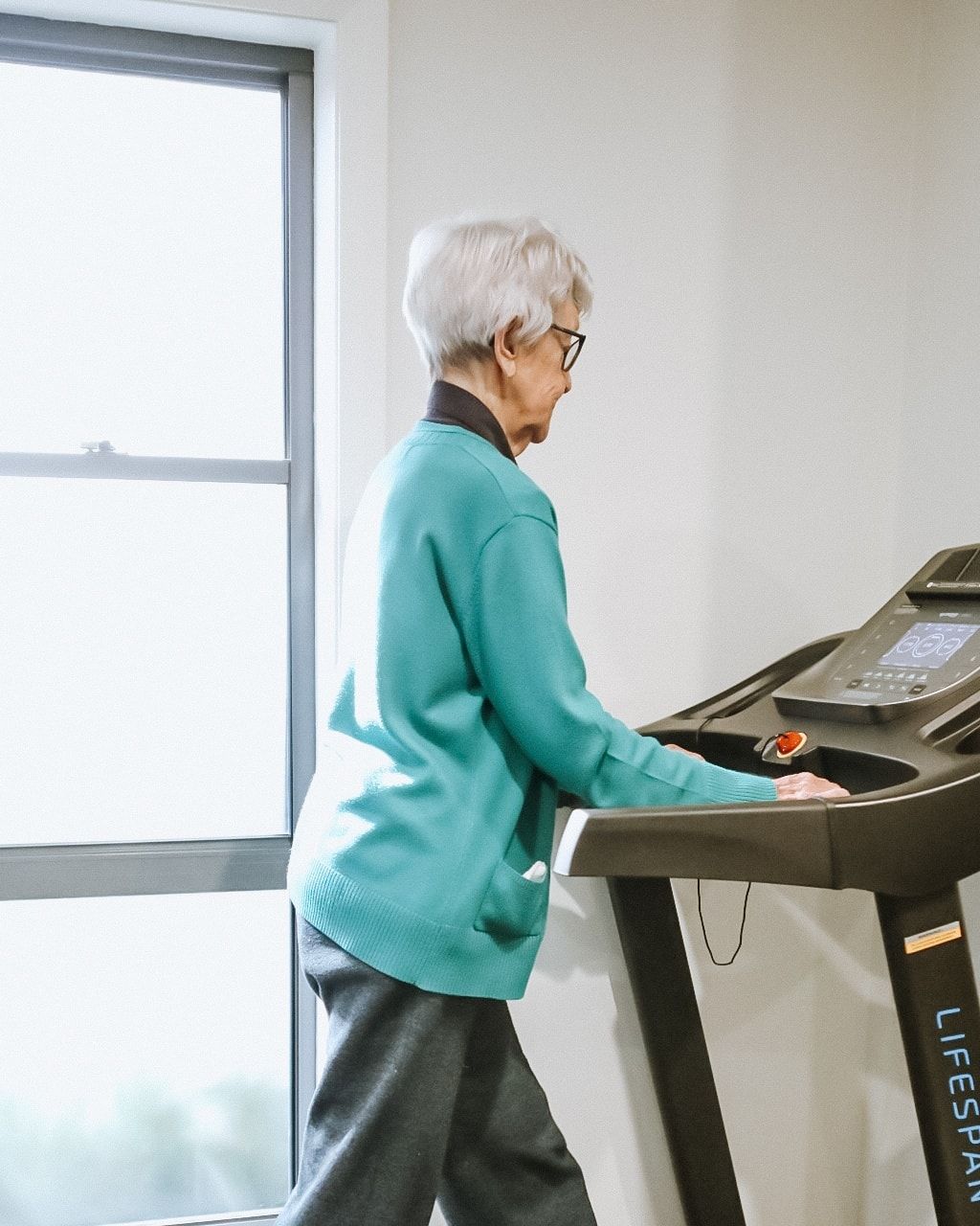 Woman in Teal Sweater Walks on a Treadmill — Forerunner Physio In Taree, NSW
