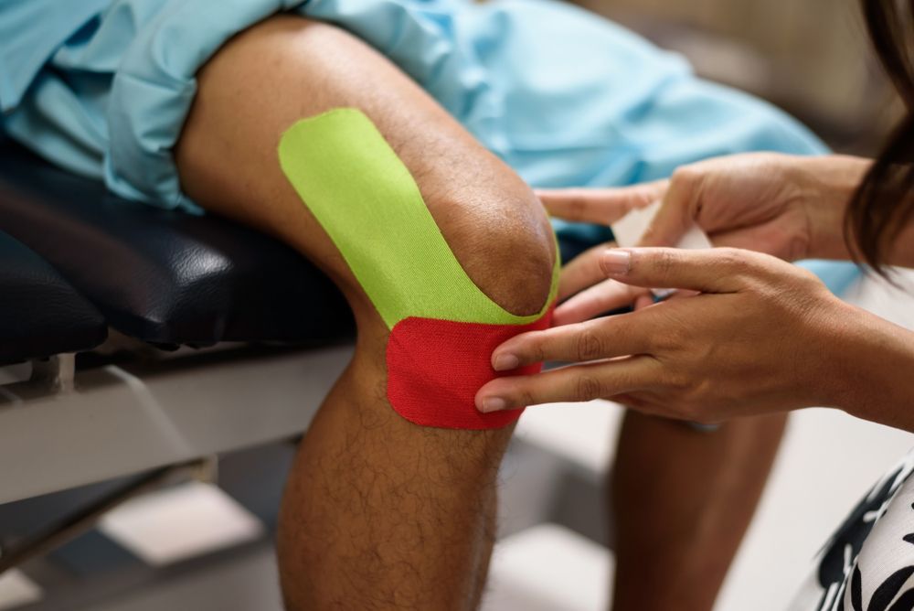 Person's Knee With Green and Red Kinesiology Tape — Forerunner Physio In Taree, NSW