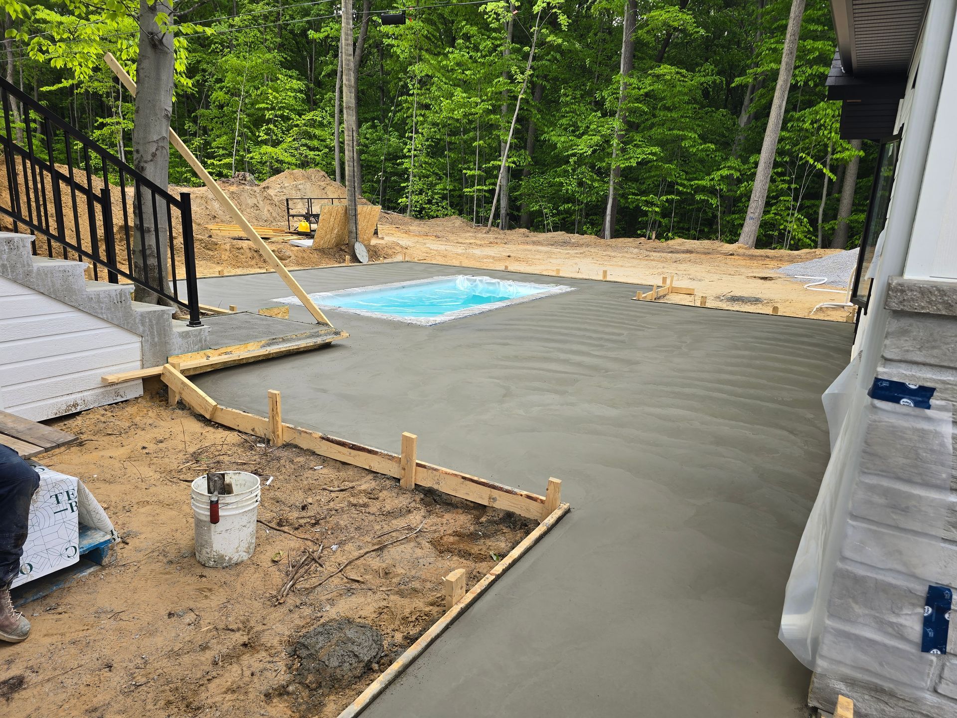 Une allée en béton est en cours de construction à côté d'une piscine.