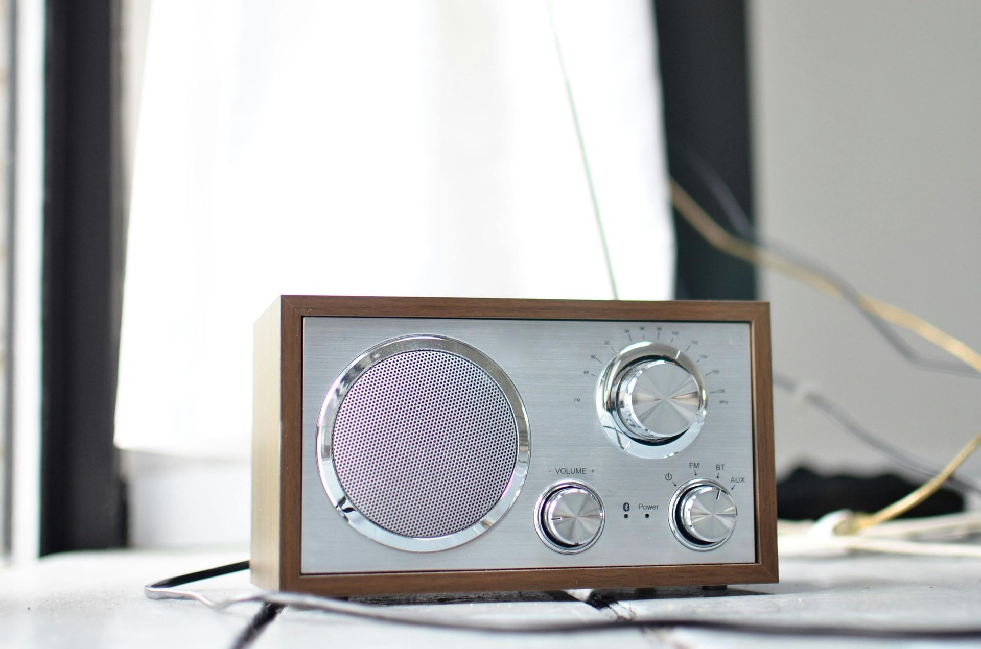 Auf einem Tisch neben einem Fenster steht ein kleines Radio.
