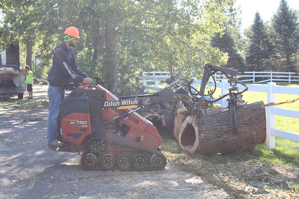 A man is using a tractor to remove a tree stump