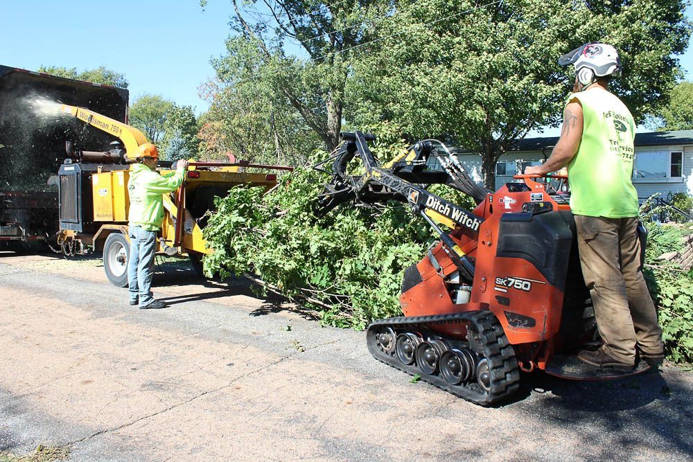 A man is standing next to a machine that is cutting trees.