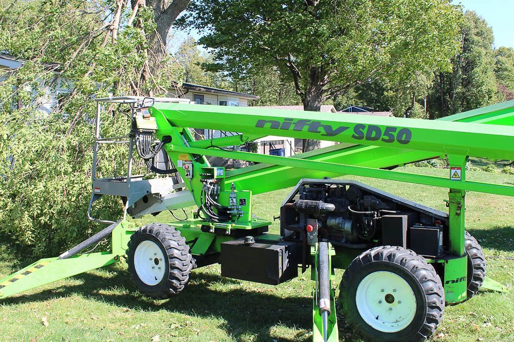 A green lift with the word nifty on it is parked in a grassy field.