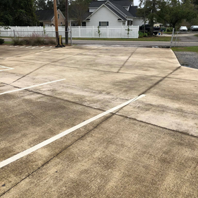 A parking lot with a white fence and a house in the background.