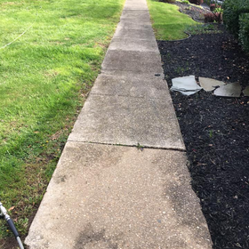 A concrete sidewalk leading to a grassy field.