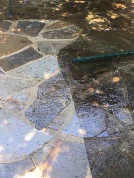 A close up of a stone patio with a hose on it.