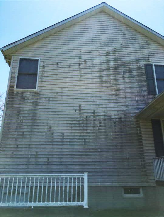 A house with a dirty siding and a white railing