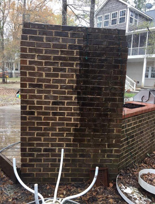 A brick wall is being cleaned with a hose in front of a house.