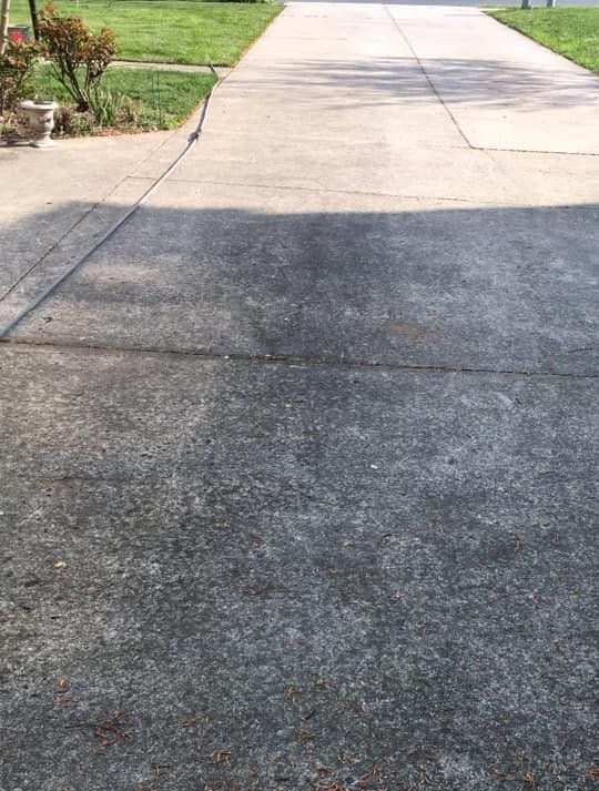 A concrete driveway with a grassy sidewalk in the background.