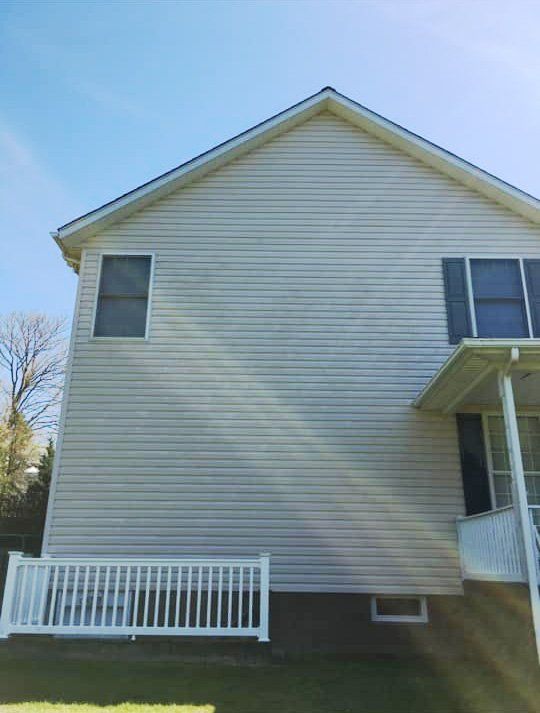 The back of a house with a white fence and a balcony.