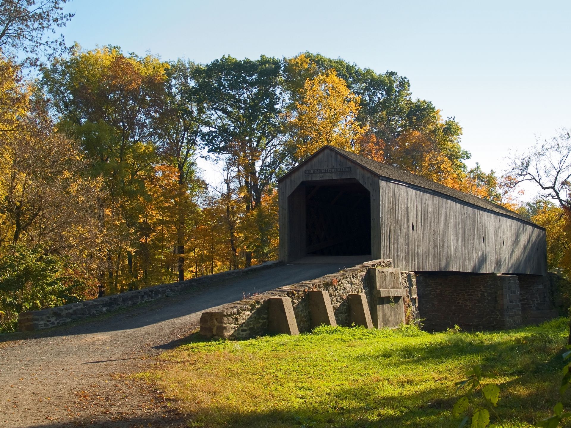 Covered wooden bridge with stone supports and autumn foliage. Covered wooden bridge with stone supports and autumn foliage.