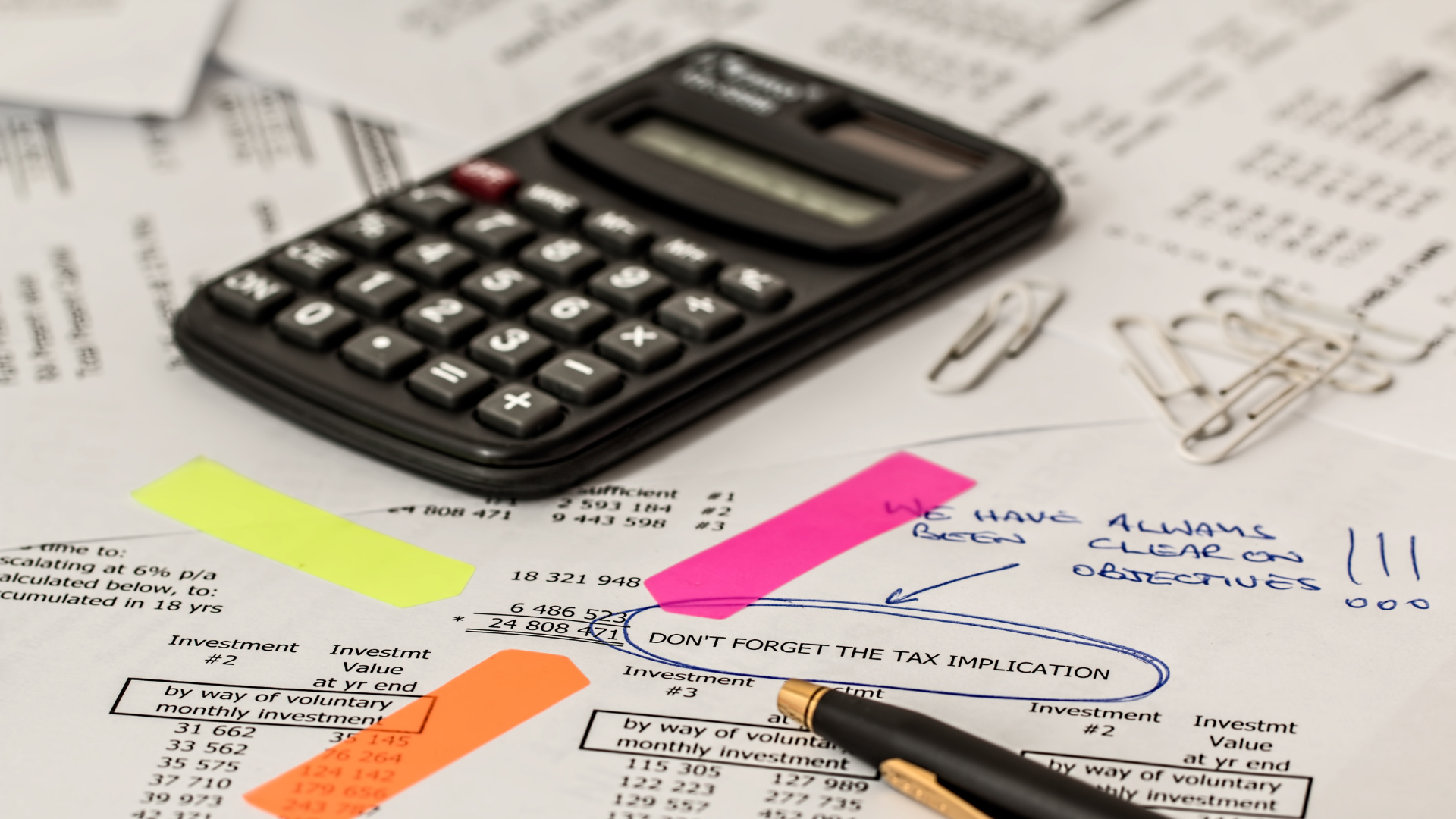 A pen is sitting on top of a pile of tax forms.