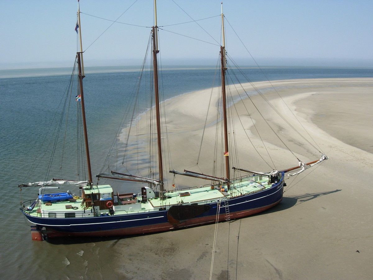 Aerial view of tall ship Morgana dried out on the Dutch Wadden Sea mudflats at low tide.