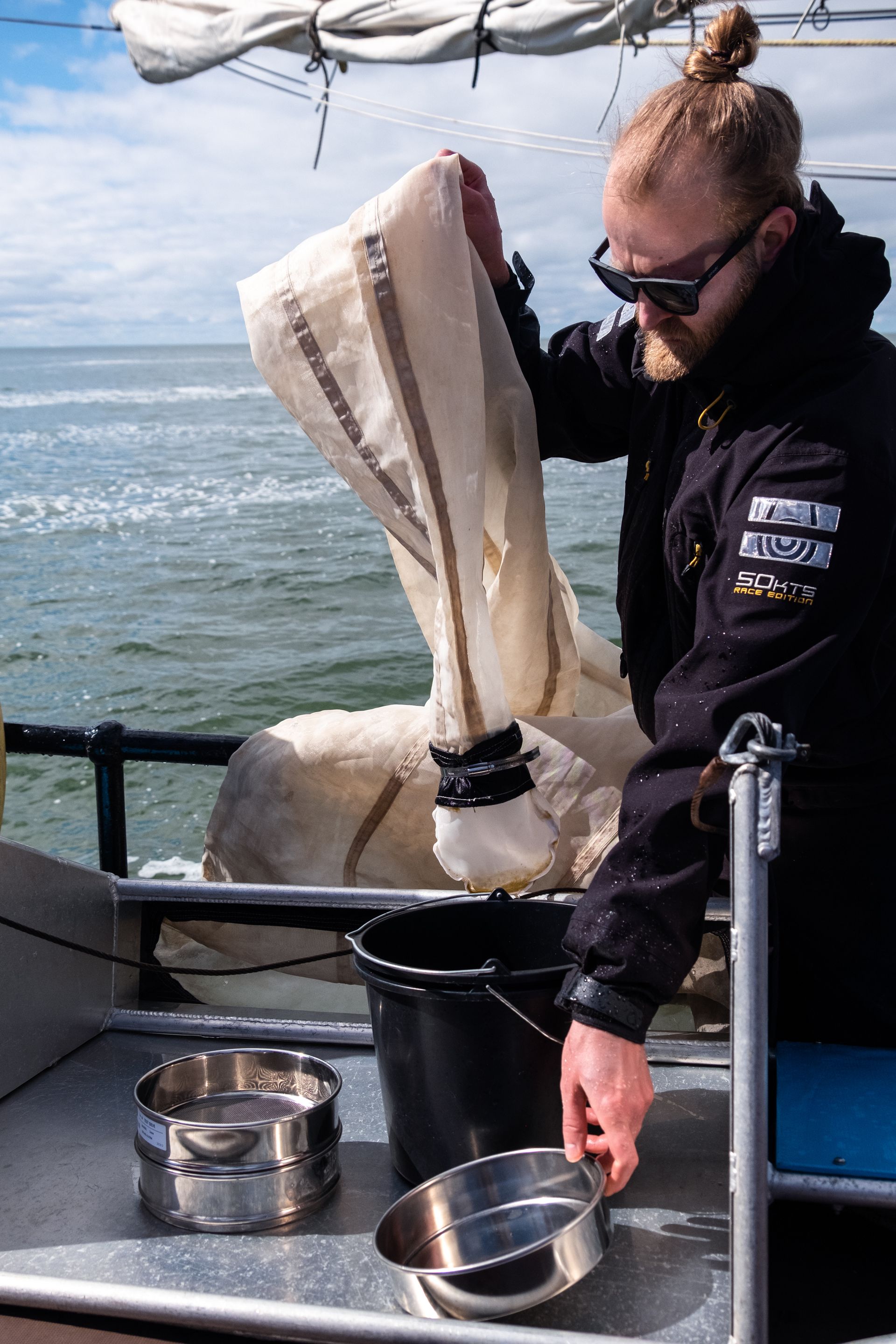 Plastic onderzoek tijdens bedrijfsuitje op de Waddenzee met The Ocean Movement –Het net van de Mantatrawl wordt uigespoeld door een man aan dek van het schip