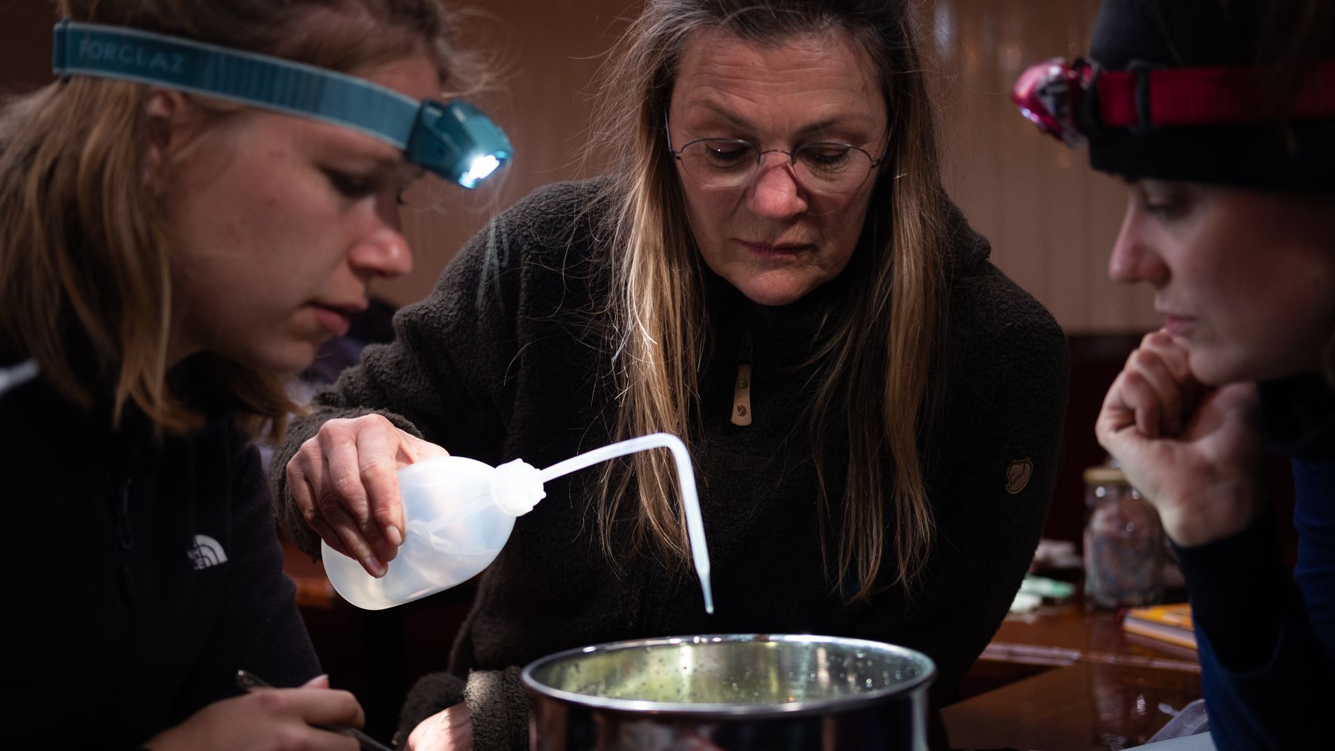 Plastic onderzoek tijdens bedrijfsuitje op de Waddenzee met The Ocean Movement –Gasten zoeken het plasticsample uit. vrouw met hoofdlamp en spuitfles