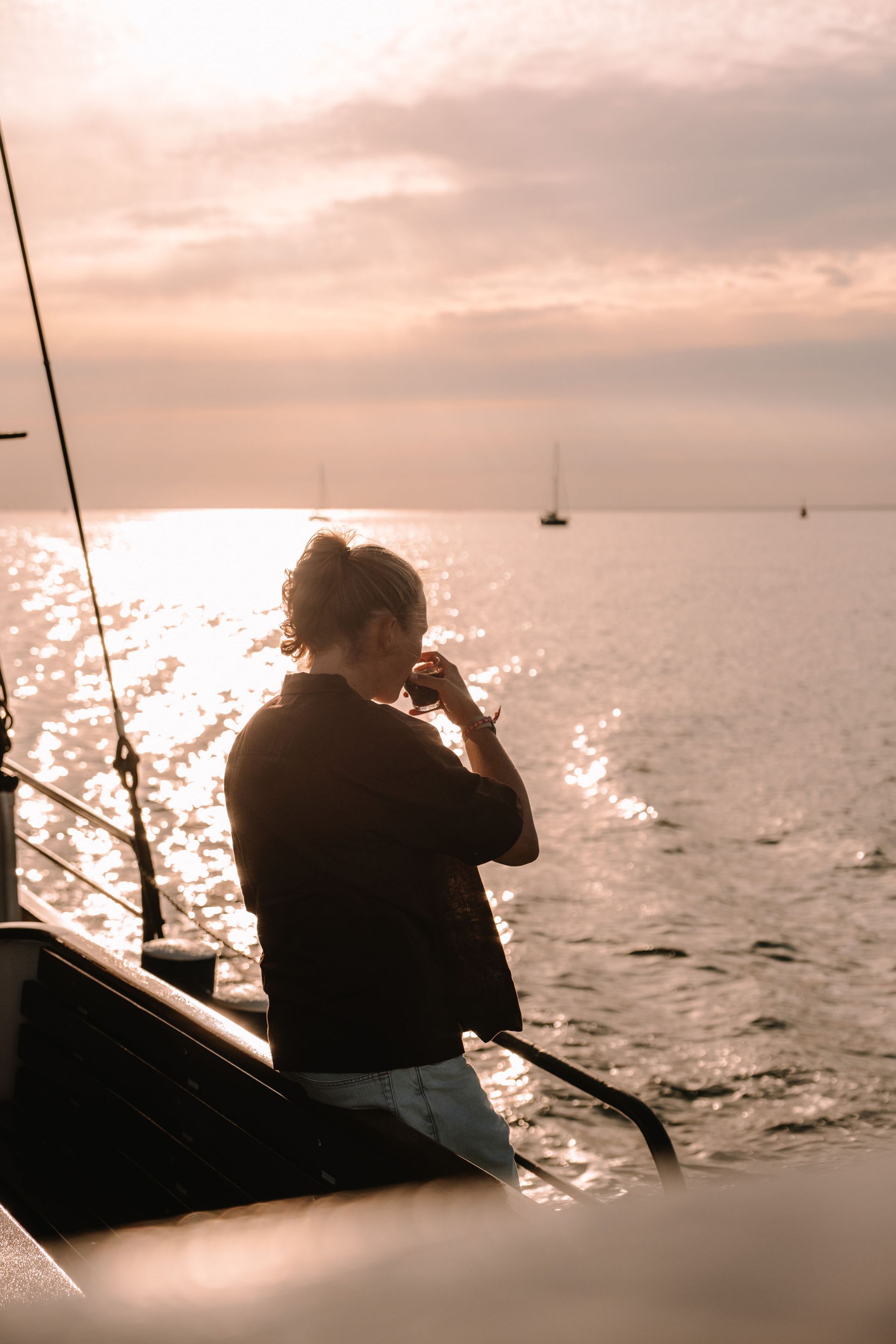 Ein Gast genießt an Bord das warme Abendlicht auf dem Wasser