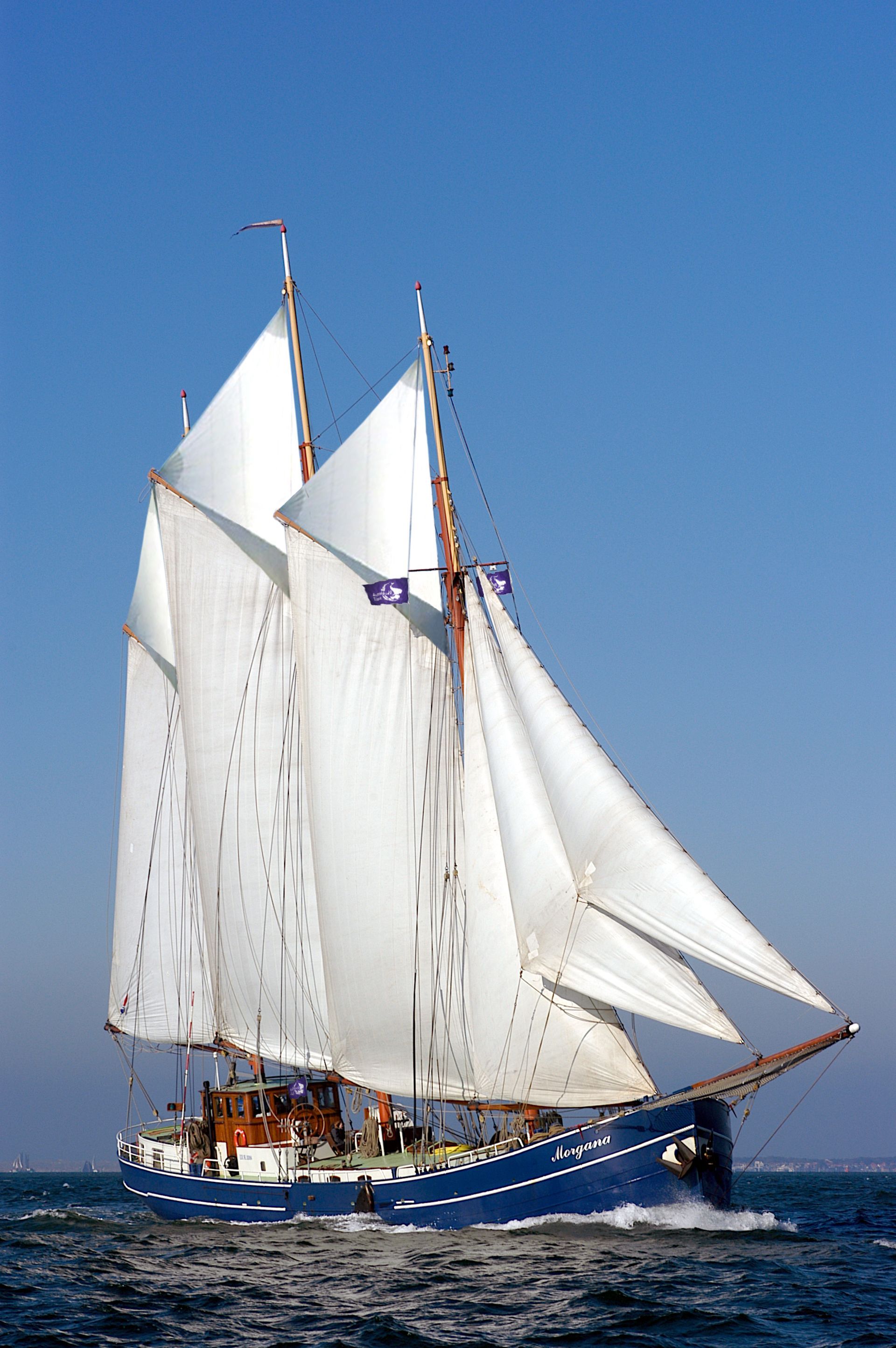 Een blauwe schoener vaart op een heldere dag met volledig witte zeilen. het is het zeilschip Morgana op de Waddenzee