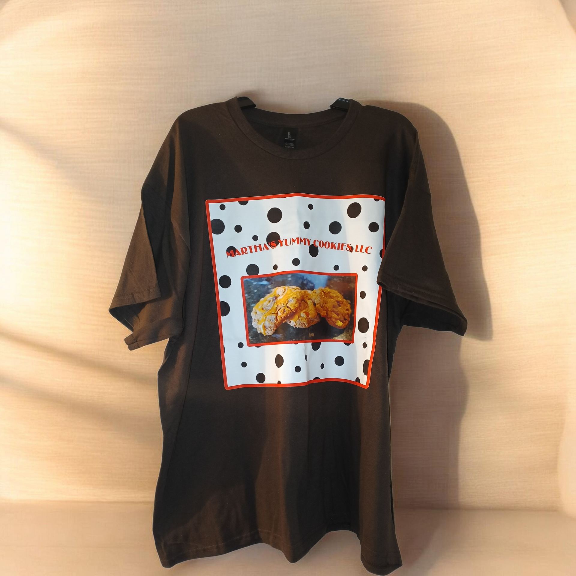 A brown t-shirt featuring a graphic with black polka dots, red outlines, and a centered photograph of fried food.