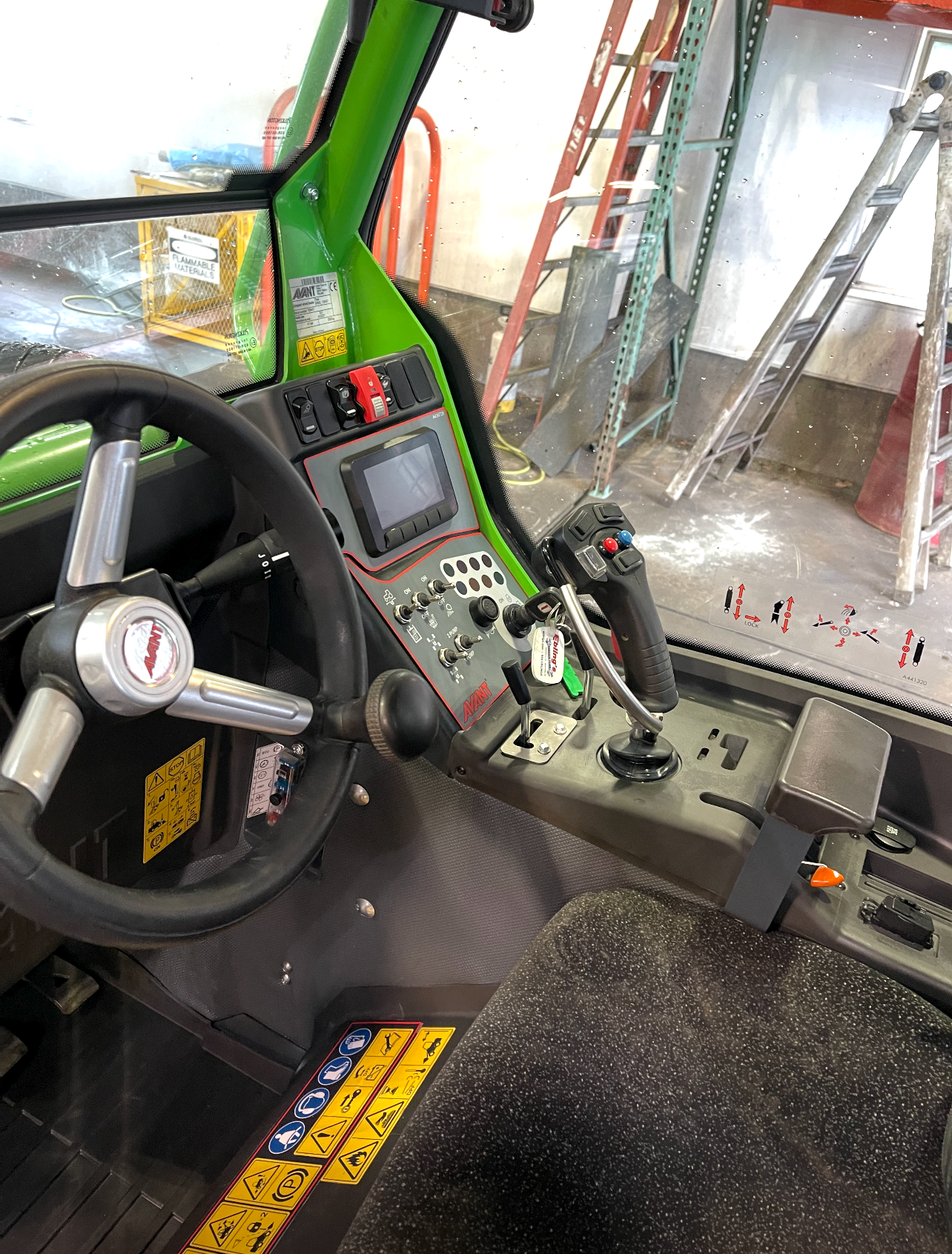 the inside of a green vehicle with a steering wheel and controls .