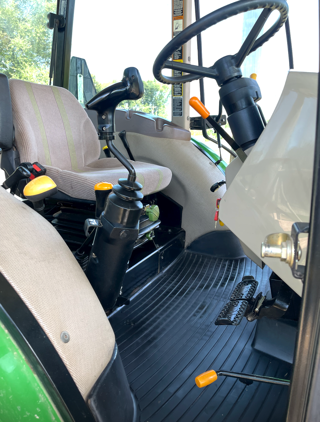the inside of a tractor with a steering wheel and seats