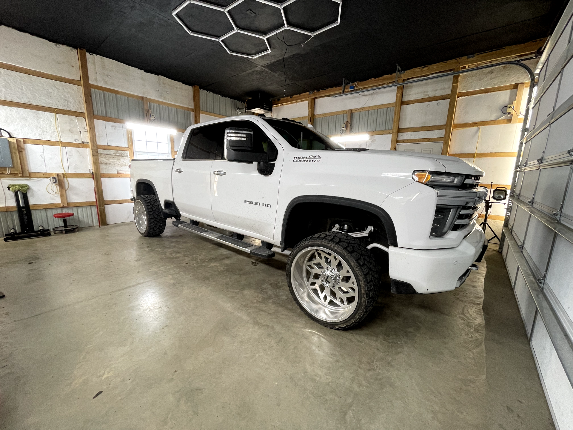 a white truck is parked in a garage next to a garage door .