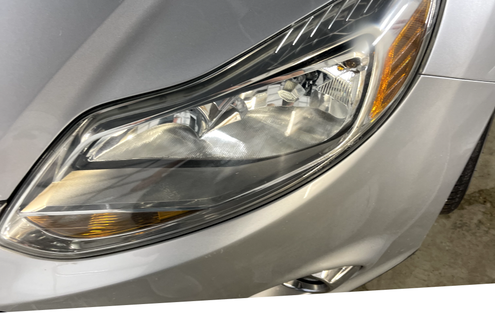 a close up of a silver car 's headlight