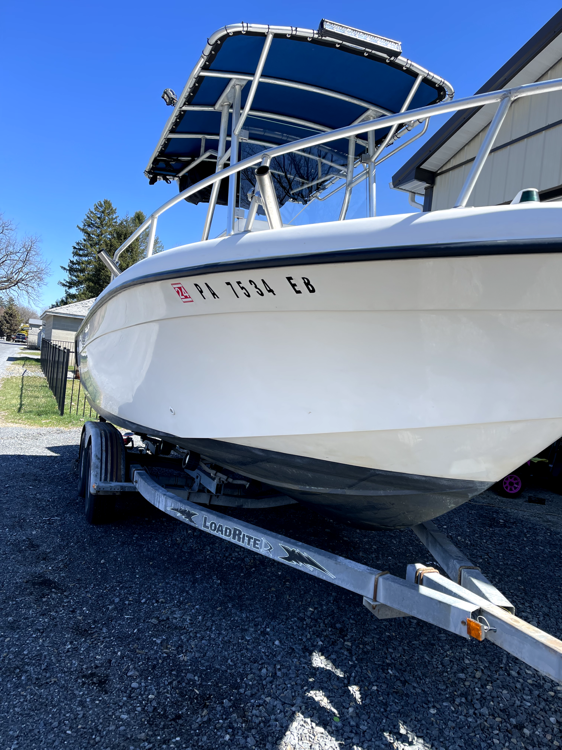 a white boat with a blue canopy is parked on a trailer .