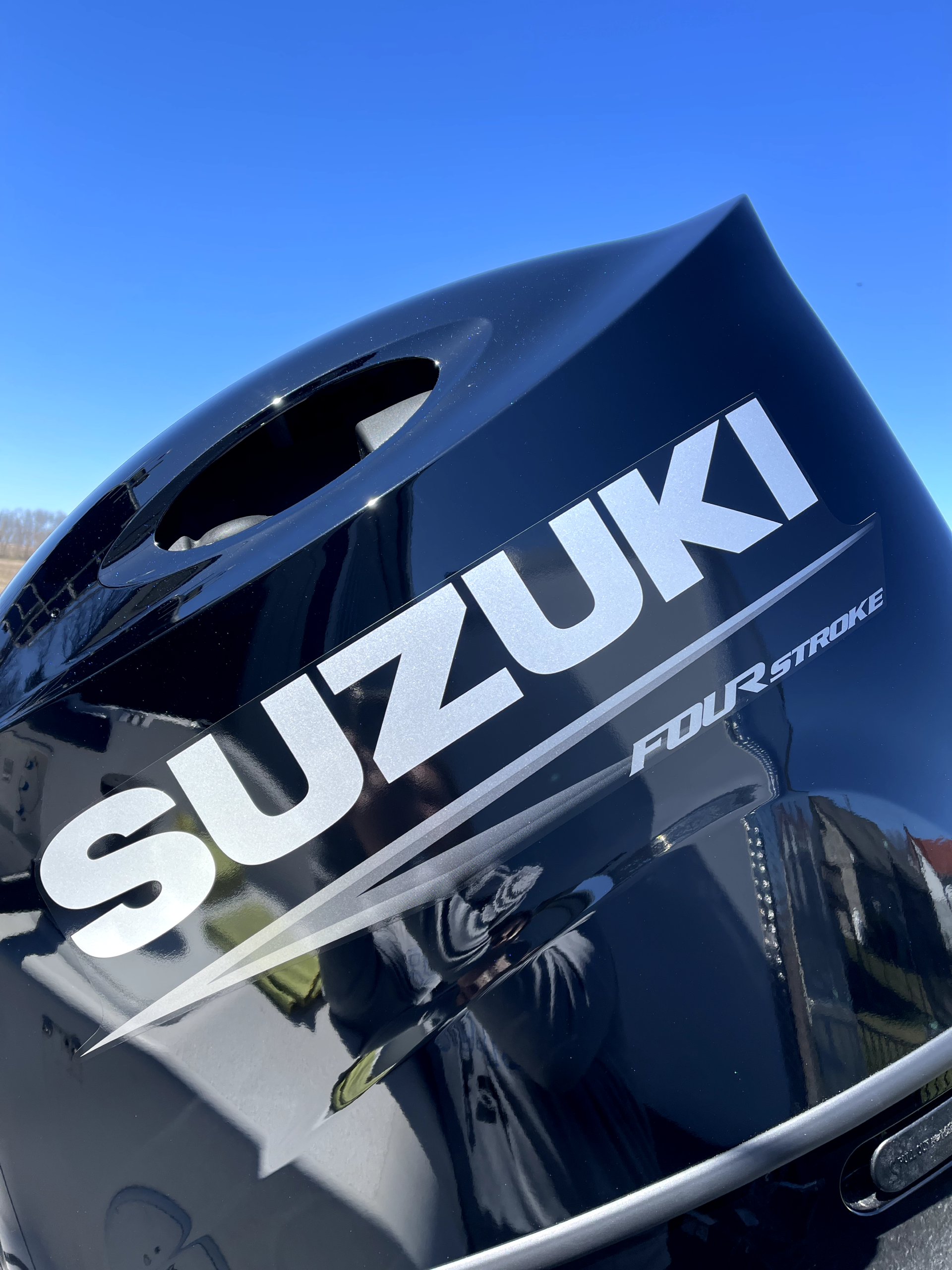 a close up of a suzuki outboard motor with a blue sky in the background .