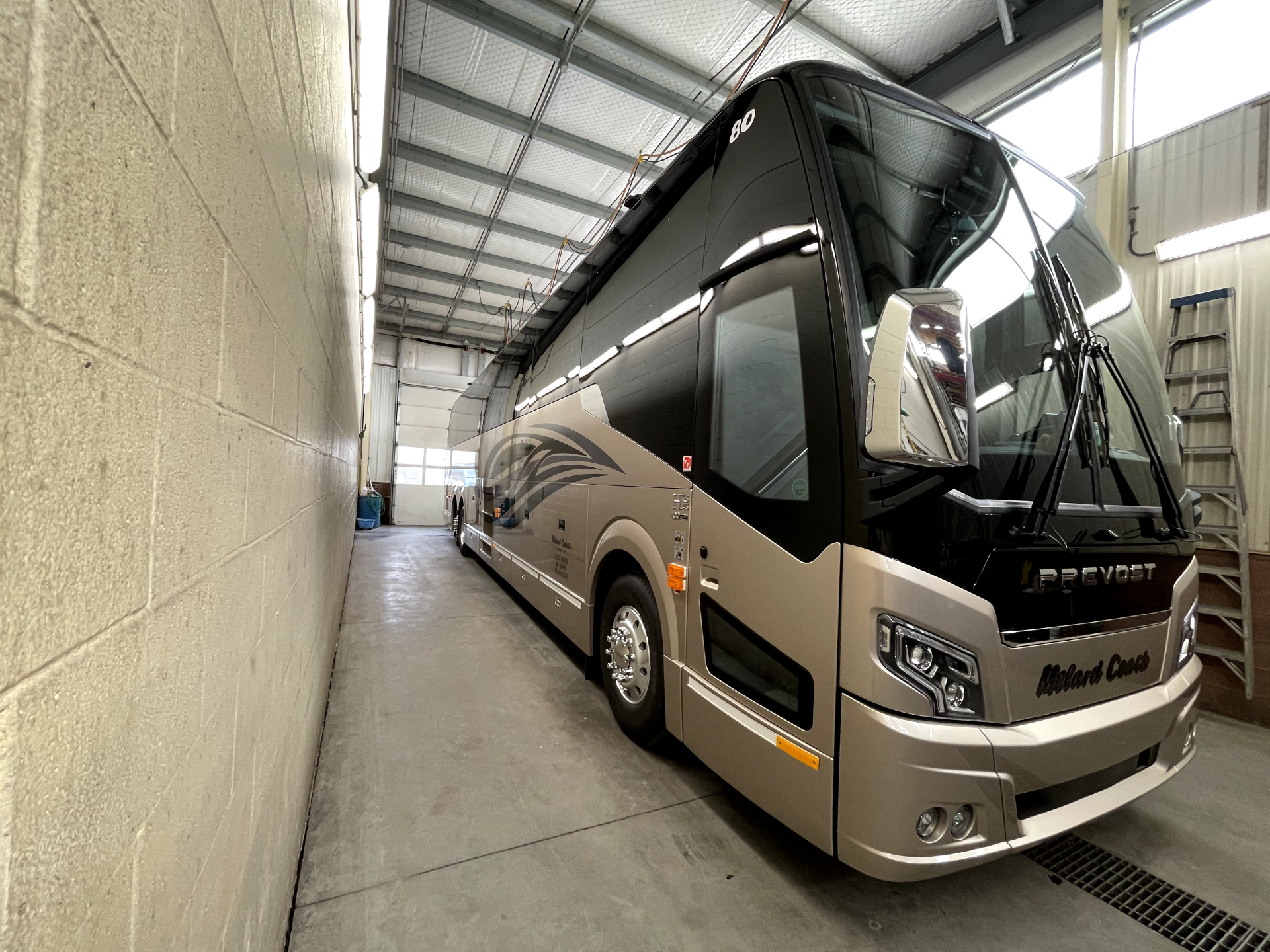 a large bus is parked in a garage next to a brick wall .