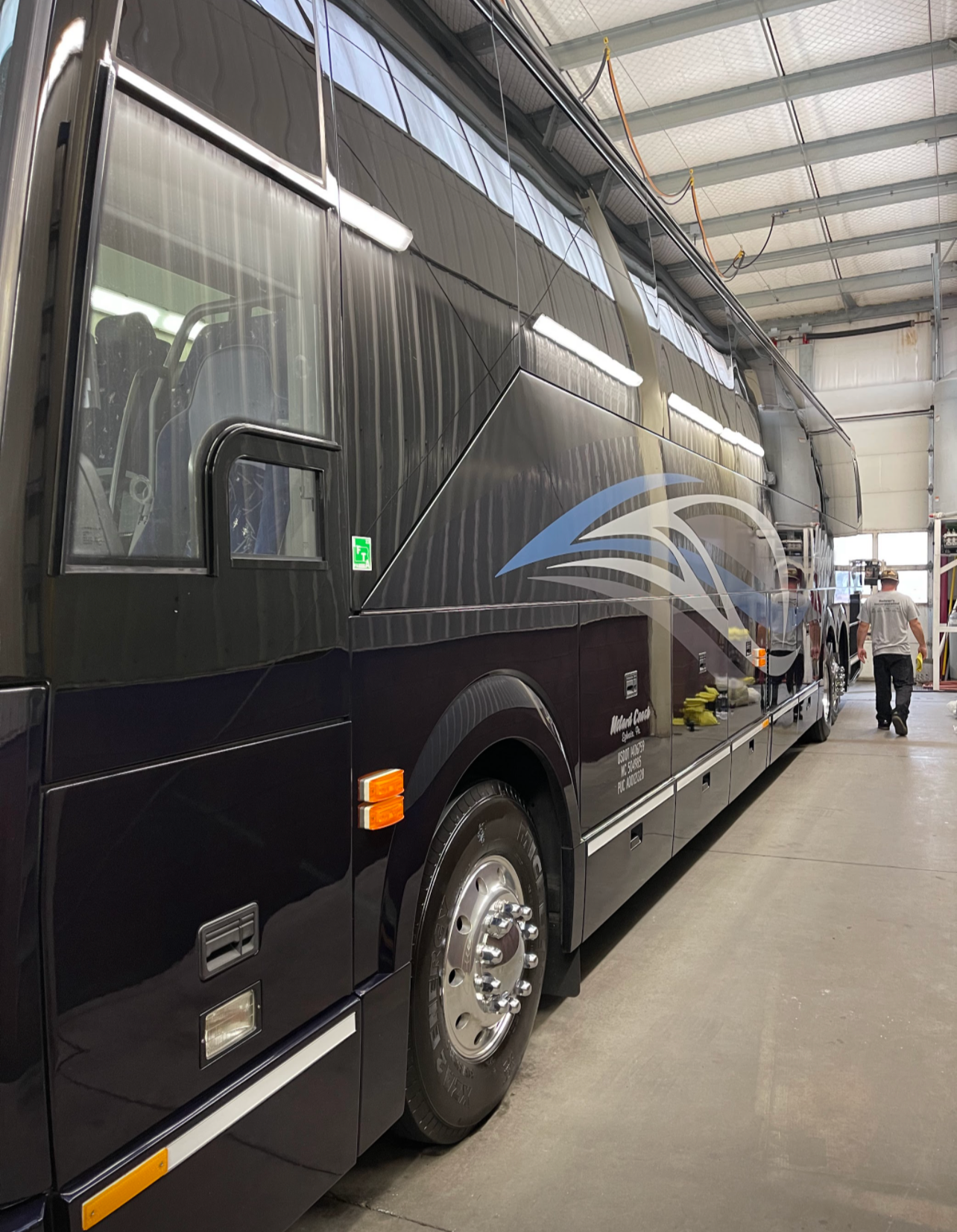 a large black bus is parked inside of a building .