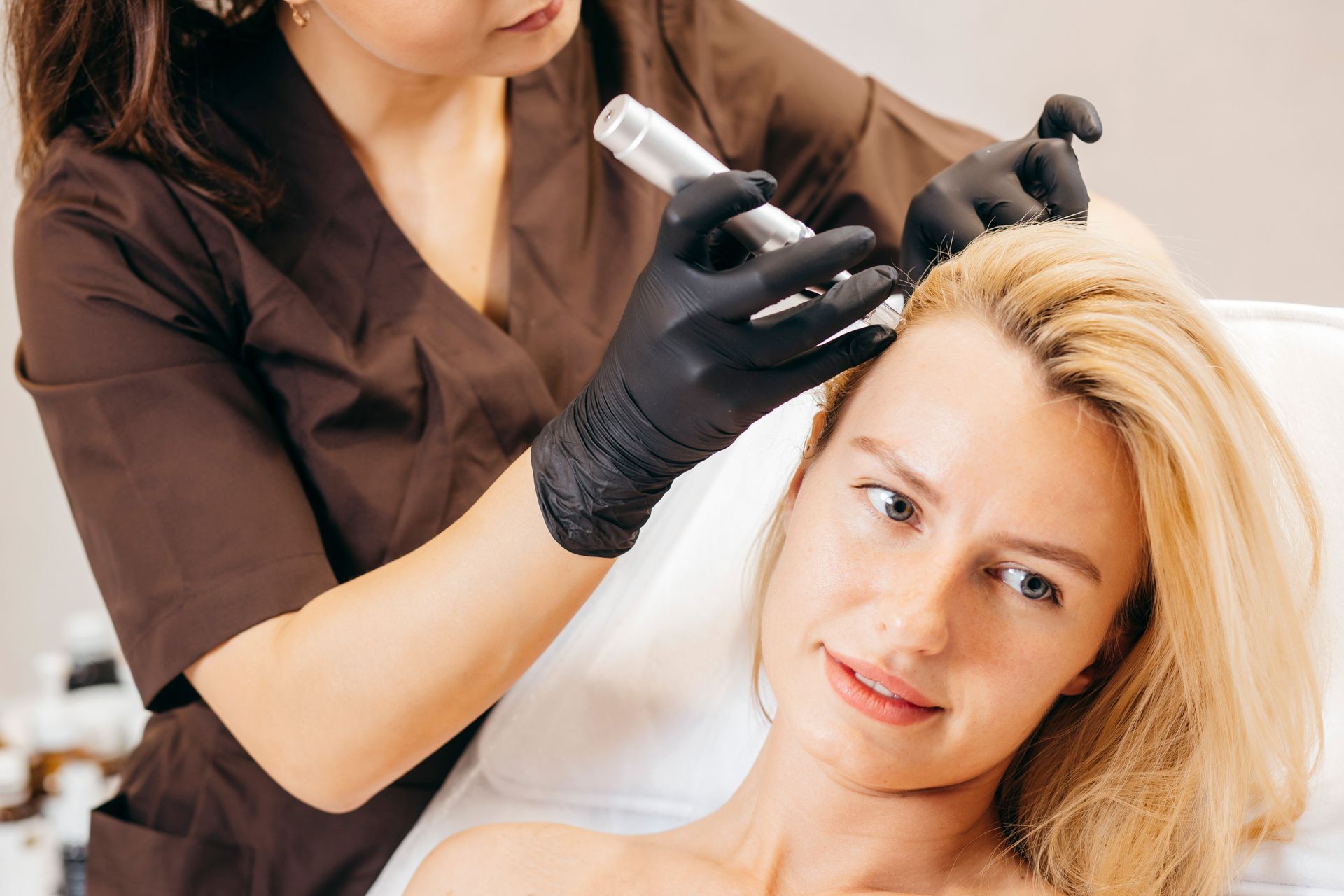 Specialist applying PRP scalp treatment to smiling woman's hair. Specialist applying PRP scalp treatment to smiling woman's hair.