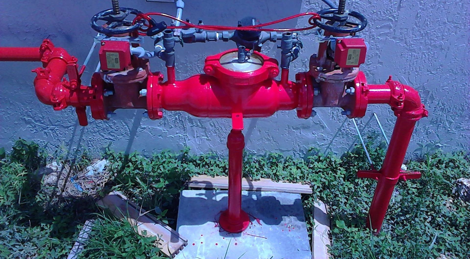 A bunch of red pipes are sitting on top of a concrete platform.