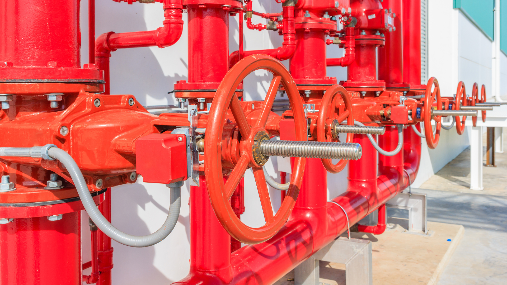 A row of red pipes and valves on a wall.