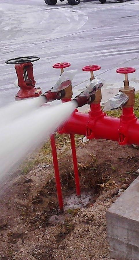 A fire hydrant is spraying water from a red pipe.