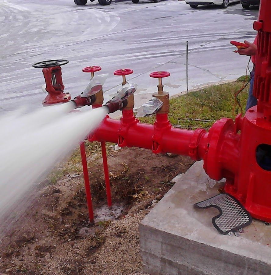 A fire hydrant is spraying water from a red pipe