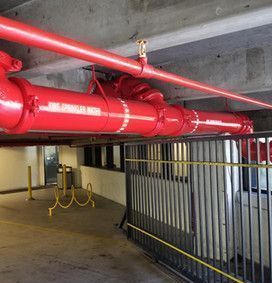 A bunch of red pipes are hanging from the ceiling of a building.