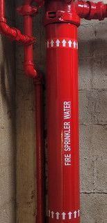 A red pipe with the words `` fire sprinkler water '' written on it.
