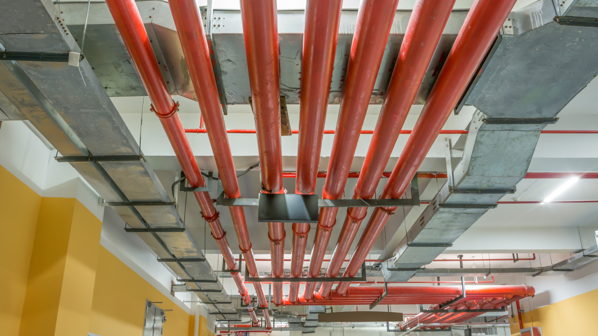 A bunch of red pipes are hanging from the ceiling of a building.