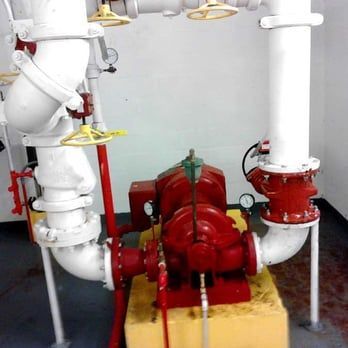 A red pump is surrounded by white pipes in a room