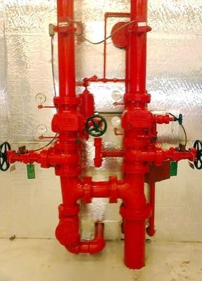 A bunch of red pipes and valves on a wall.