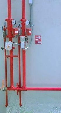 A bunch of red pipes are hanging on a wall.
