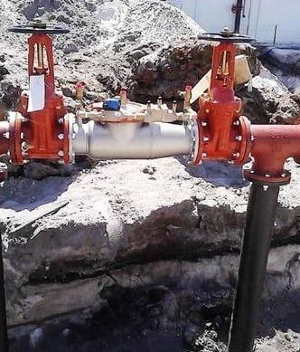 A couple of red valves are sitting on top of a pile of rocks.