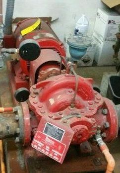 A red pump is sitting on top of a wooden table.