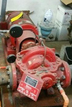 A red fire pump is sitting on top of a wooden table.