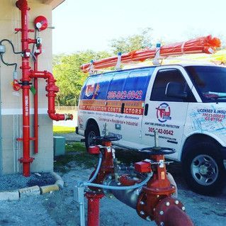 A van is parked next to a building with red pipes.