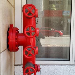 A red fire hydrant is attached to the side of a building.