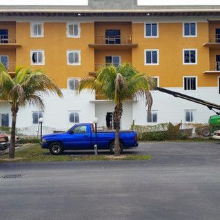 A blue truck is parked in front of a large yellow building.