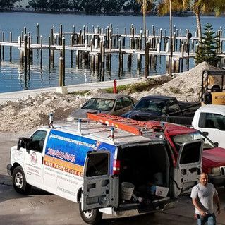 A van with a ladder on top of it is parked next to a body of water.
