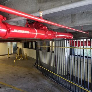 A bunch of red pipes are hanging from the ceiling of a building